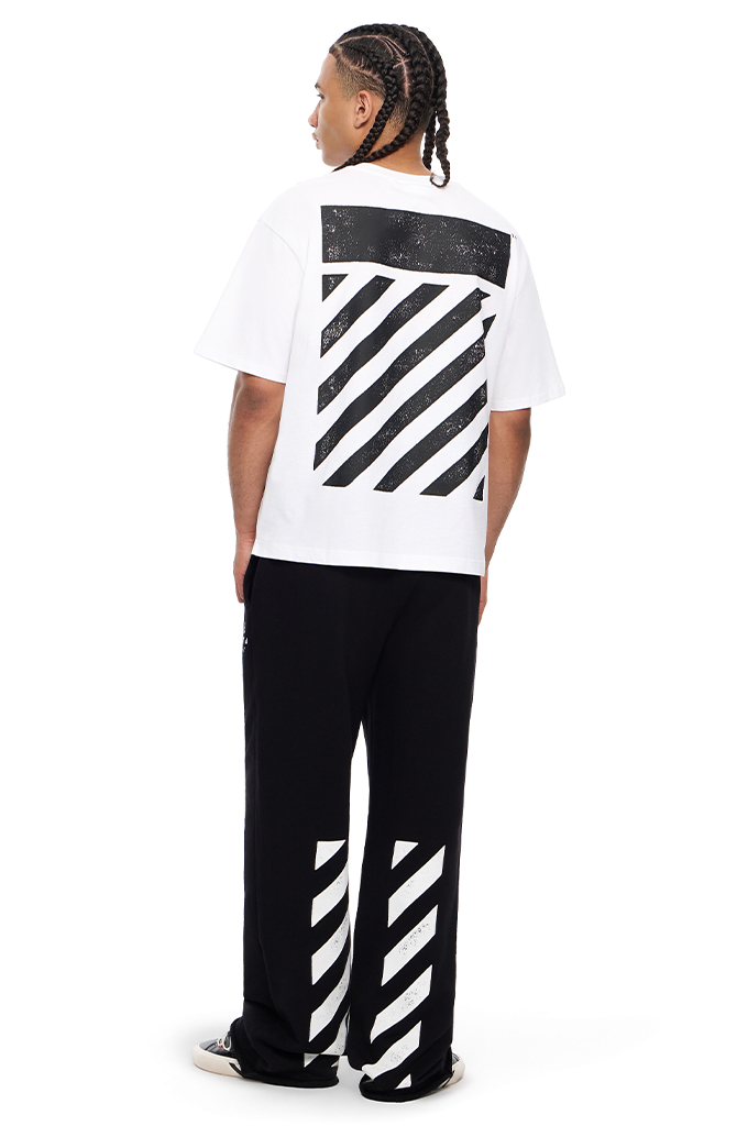 A model shown from the back wearing a white t-shirt and black sweatpants, both featuring the signature diagonal striped Off-White logo design.#color_white