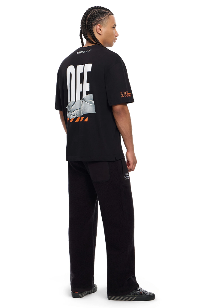 A model shown from the back wearing a black Off-White t-shirt with a large white and orange graphic print, paired with black sweatpants and black sneakers, on a solid white background.#color_black