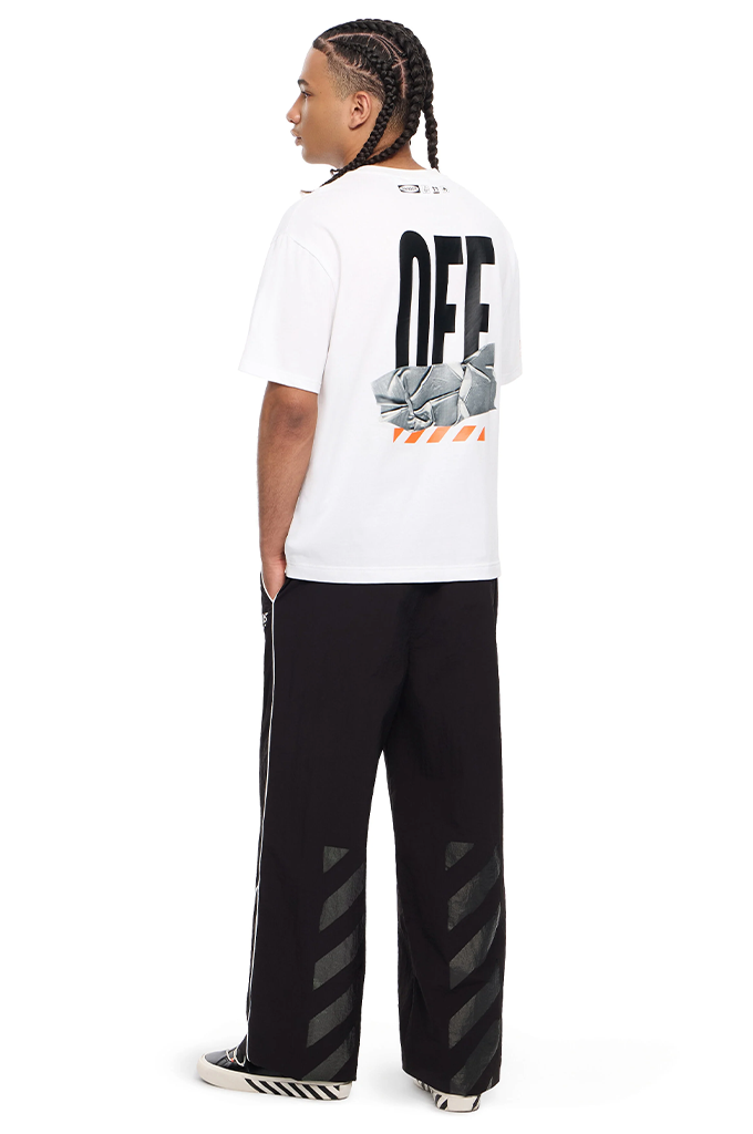 A man shown from the back wearing a white Off-White t-shirt with a large black and gray graphic print, paired with black wide-leg pants featuring diagonal gray stripe details on the lower legs, against a plain white background.#color_white