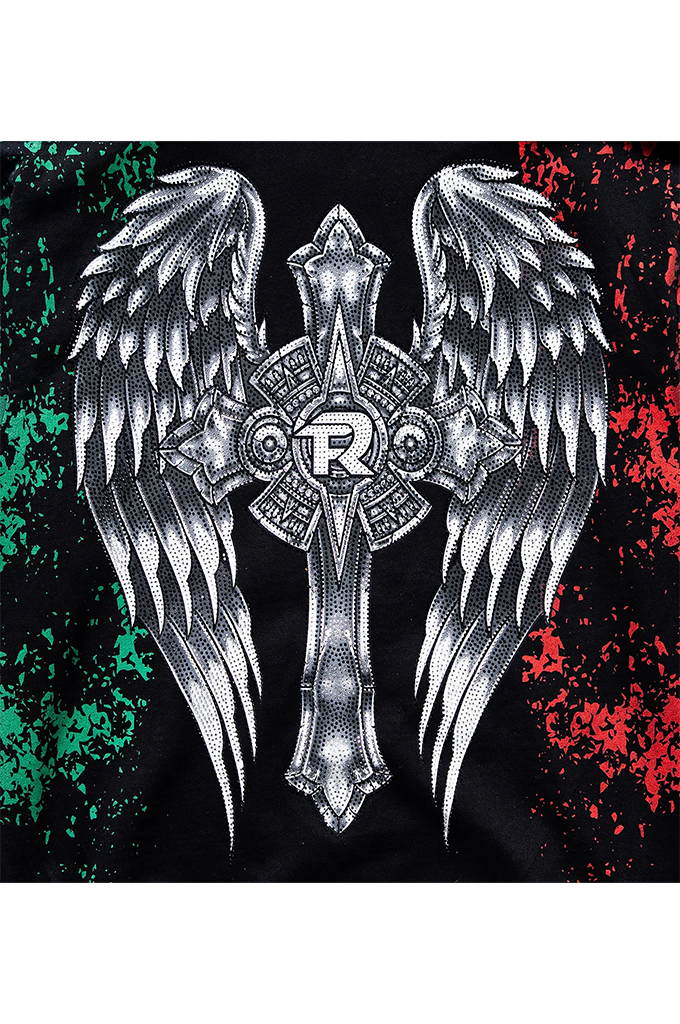 A close-up of a black garment featuring a large graphic print of a silver angel winged cross. The design is flanked by green distressed paint splatters on the left and red distressed paint splatters on the right.