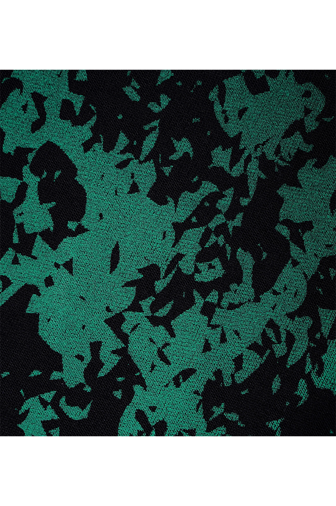 A close-up of a textured fabric with an abstract camouflage pattern in dark green and black.
