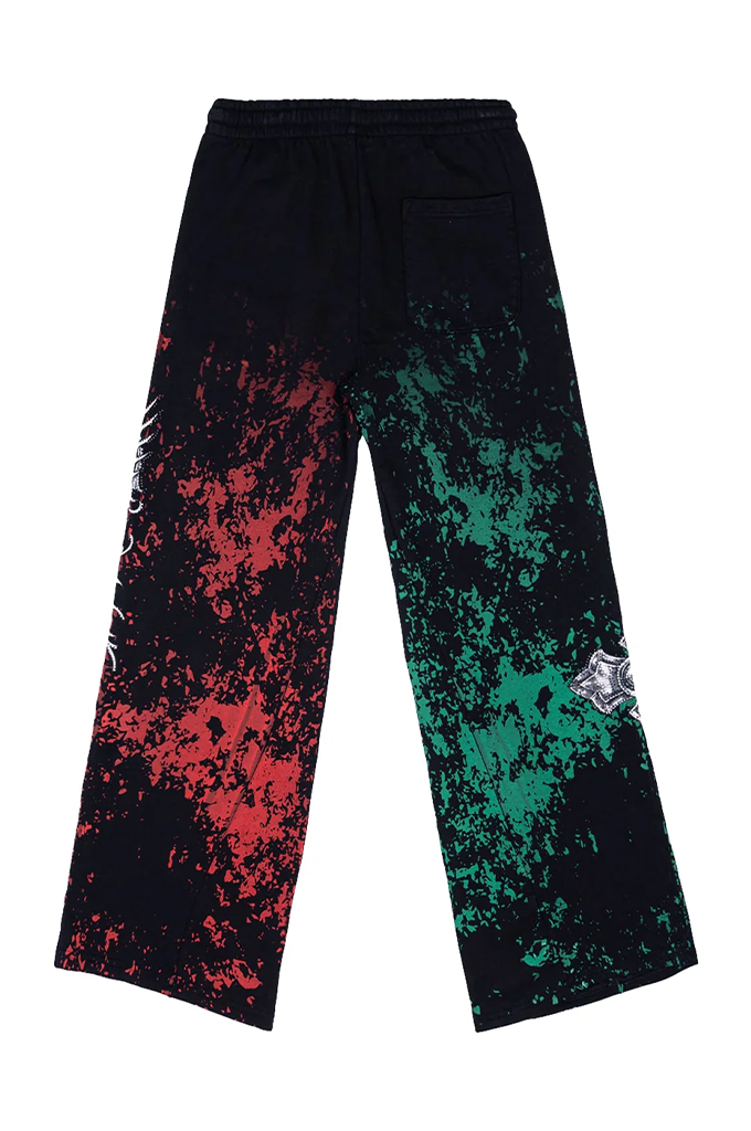 A pair of wide-leg sweatpants with a black base featuring a red splatter pattern on the left leg and a green splatter pattern on the right leg, shown against a plain white background.