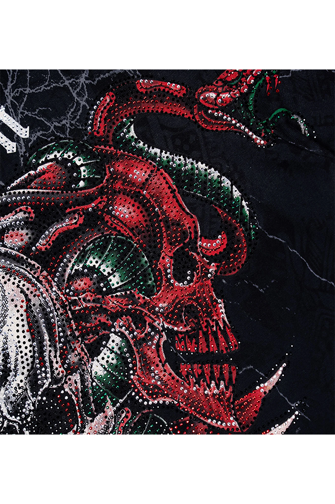 A close-up of a black fabric featuring a highly detailed graphic print of a skull and serpent design, embellished with red, green, and silver rhinestones.