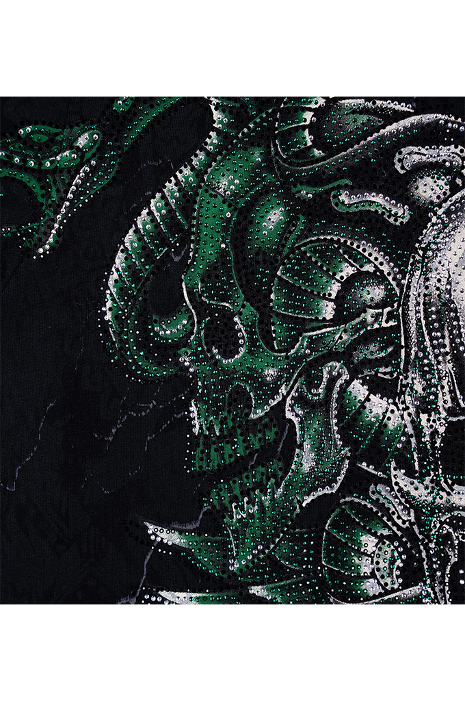A close-up of a black fabric featuring a detailed green and white dotted graphic of a horned skull and dragon motif.