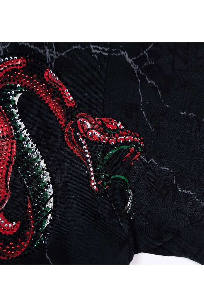 Close-up of a black textured garment featuring a large sequined snake design in red, green, and silver.