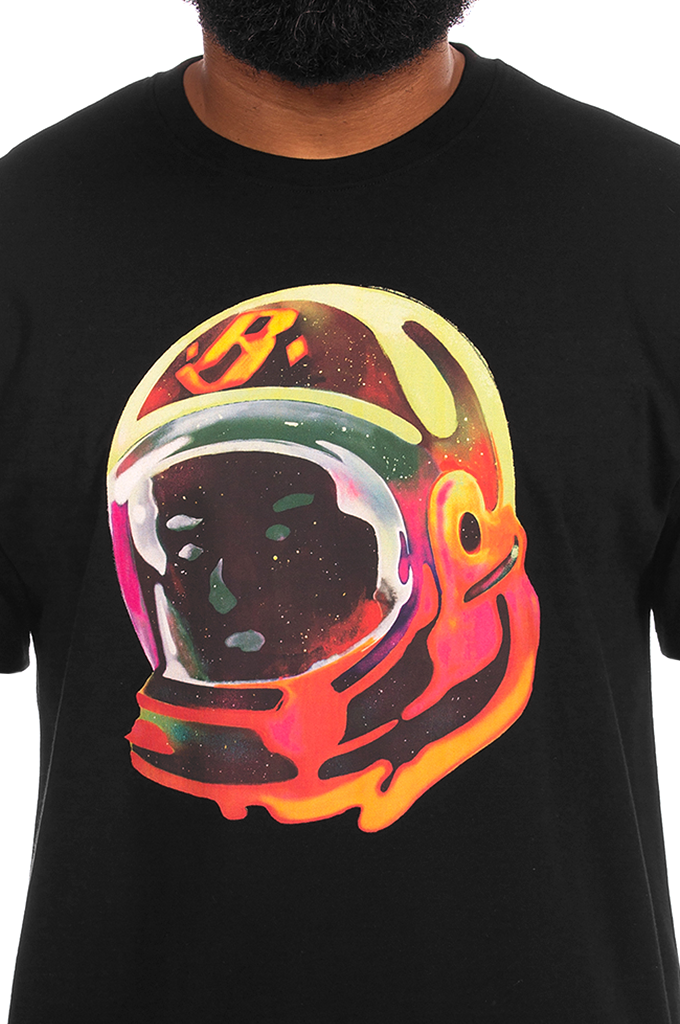 A close-up of a person wearing a black t-shirt with a large, colorful graphic of a retro astronaut helmet on the chest. The graphic features a yellow, orange, and red drip design with a dark visor.