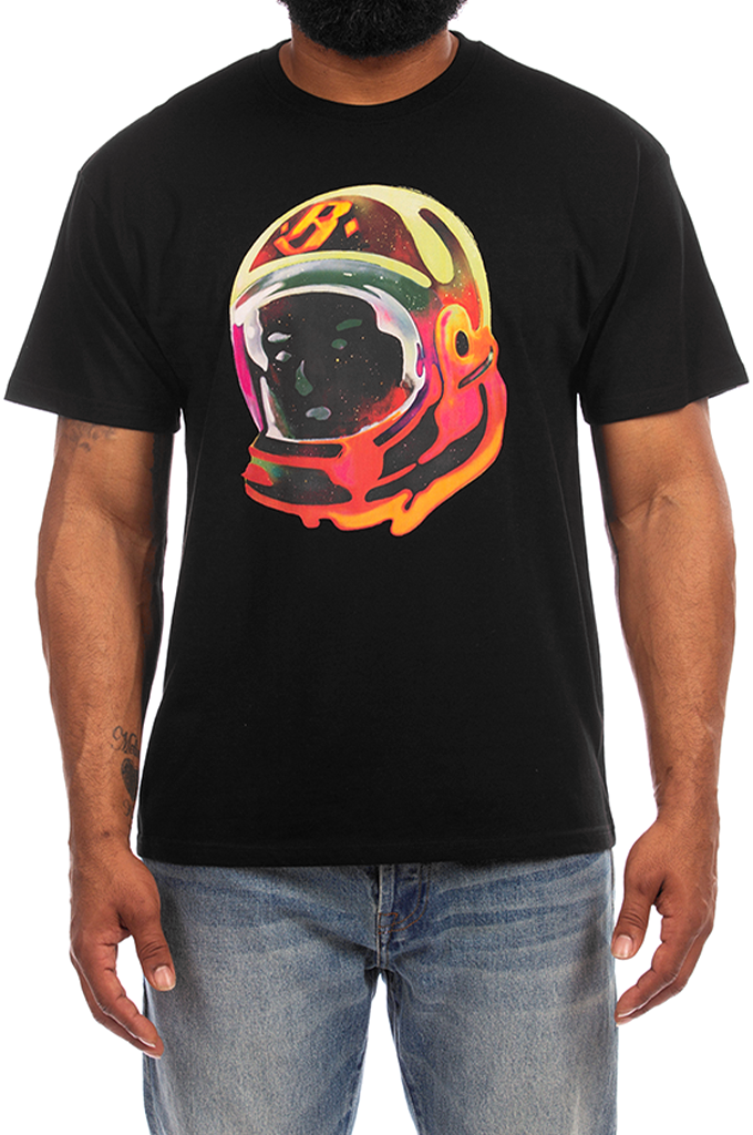 A man wearing a black short-sleeve t-shirt with a colorful graphic of an astronaut helmet on the chest, paired with blue jeans against a white background.