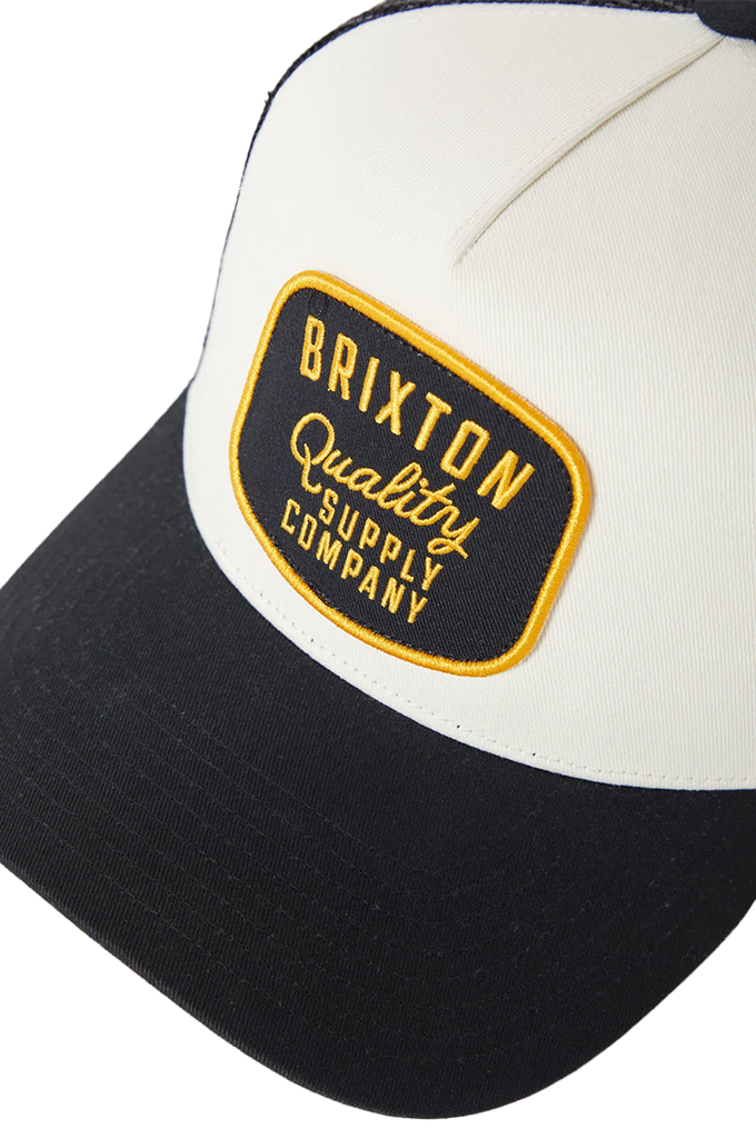 Brixton Hubal NetPlus Trucker Hat in black and off-white, featuring an embroidered "Brixton Quality Supply Company" patch on the front panel.