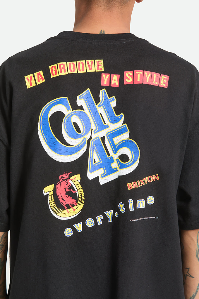 A back view of a person wearing a black oversized crewneck t-shirt featuring retro-style graphics. At the top, the words "YA GROOVE" and "YA STYLE" are printed in yellow letters inside red rectangular blocks. Below this, "Colt 45" is written in a large, stylized blue cursive font with a white and blue drop shadow. Below the lettering is a yellow horseshoe enclosing a pink silhouette of a bucking horse, next to the brand name "BRIXTON" in orange. The phrase "every.time" is printed across the bottom.