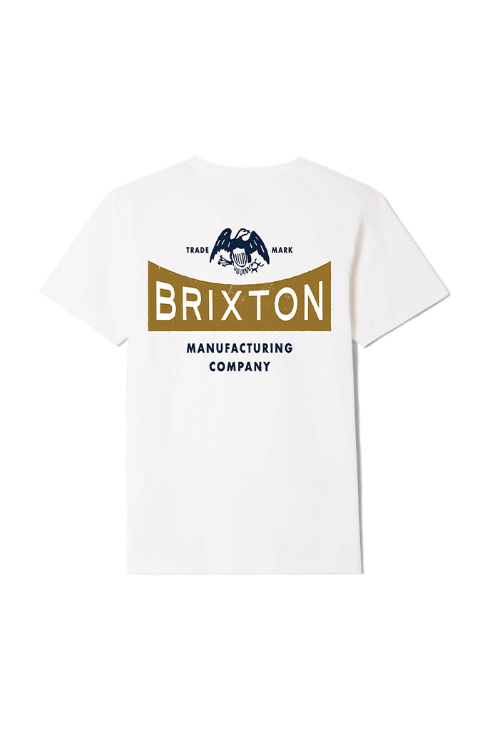 The back of a white short-sleeve crewneck t-shirt featuring a large graphic print. The design displays a dark blue eagle emblem with "TRADE" and "MARK" on either side, positioned above a gold-colored horizontal banner containing the word "BRIXTON" in bold white capital letters. Below the banner, the words "MANUFACTURING COMPANY" are printed in clean, dark blue block lettering. #color_white