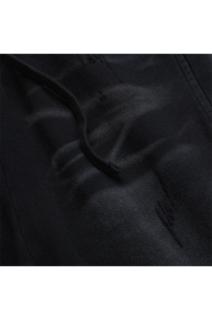 Close-up of a black textured fabric garment with a tonal embroidered logo and a black drawstring, shown against a white background.