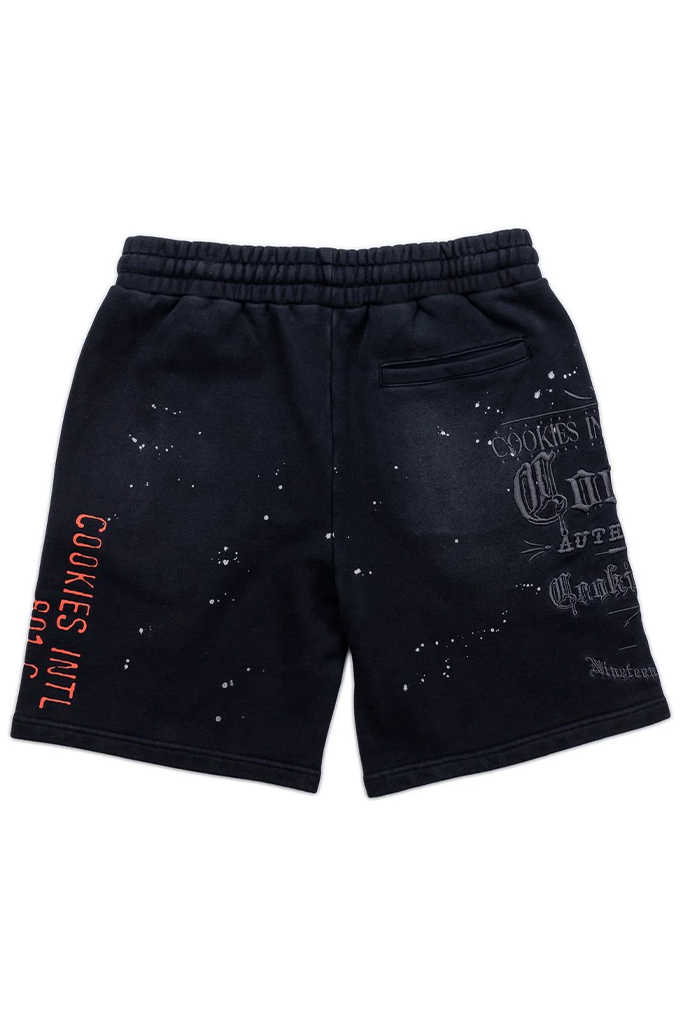 Black sweat shorts with a distressed, faded look, featuring orange text on the left leg and white graphic text on the right leg, shown against a plain white background.