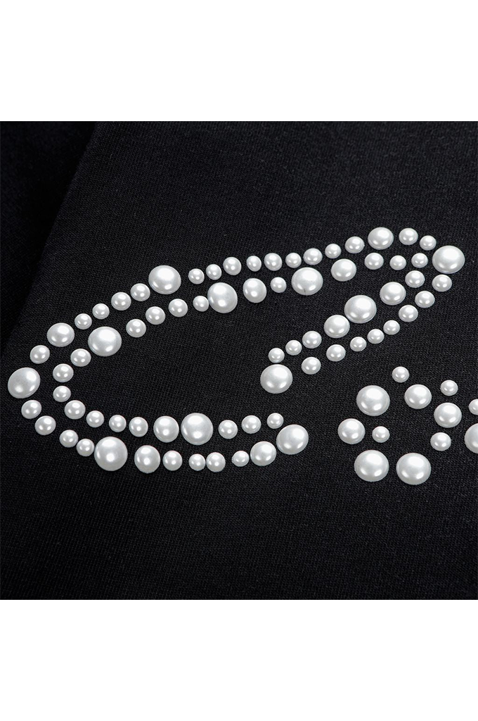 White faux-pearl rhinestones arranged in a decorative curved pattern on a black fabric background.