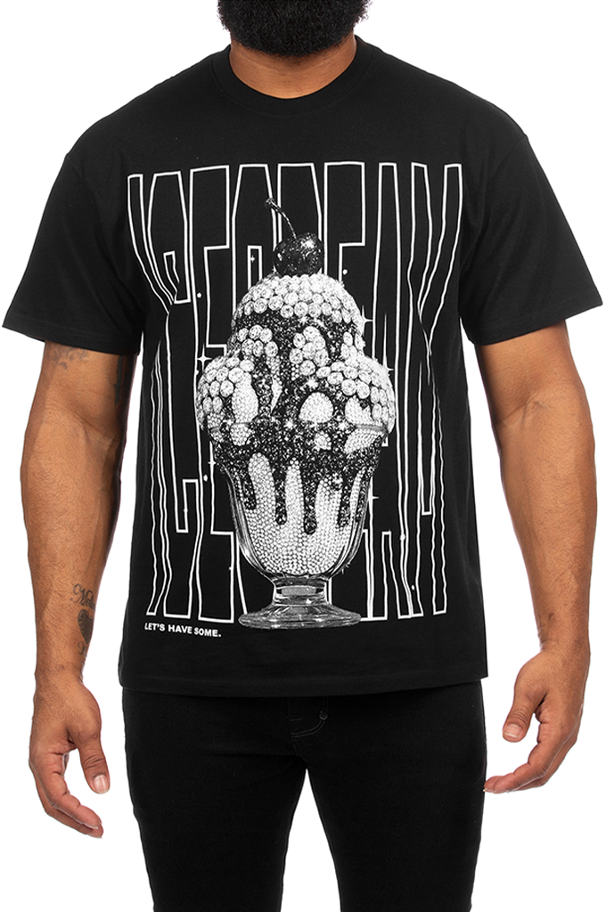 A man wearing a black graphic t-shirt featuring a large white and black ice cream sundae design with the word 'ICECREAM' in vertical lines, paired with black pants against a white background.