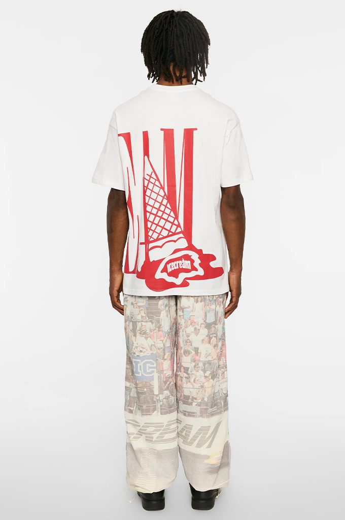 ICECREAM men's Chai short sleeve streetwear graphic t-shirt in white, featuring a melting red ice cream cone graphic on the back, styled with patterned pants. #color_white