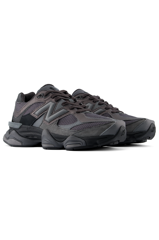 Angled view of a New Balance 9060 sneaker in a black and grey colorway, featuring its signature chunky, sculpted midsole.#color_black-grey-castlerock