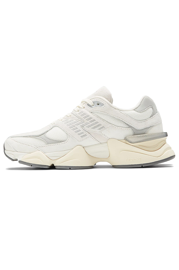 A side-profile view of a New Balance 9060 sneaker. The shoe features a retro-futuristic style with a chunky, sculpted cream and grey midsole. The upper is made of off-white mesh and suede overlays, with a metallic silver "N" logo on the side. #color_white-grey-sea-salt-concrete
