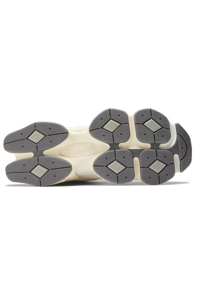 Bottom view of a New Balance 9060 sneaker. The shoe features a retro-futuristic style with a chunky, sculpted cream and grey midsole. The upper is made of off-white mesh and suede overlays, with a metallic silver "N" logo on the side. #color_white-grey-sea-salt-concrete