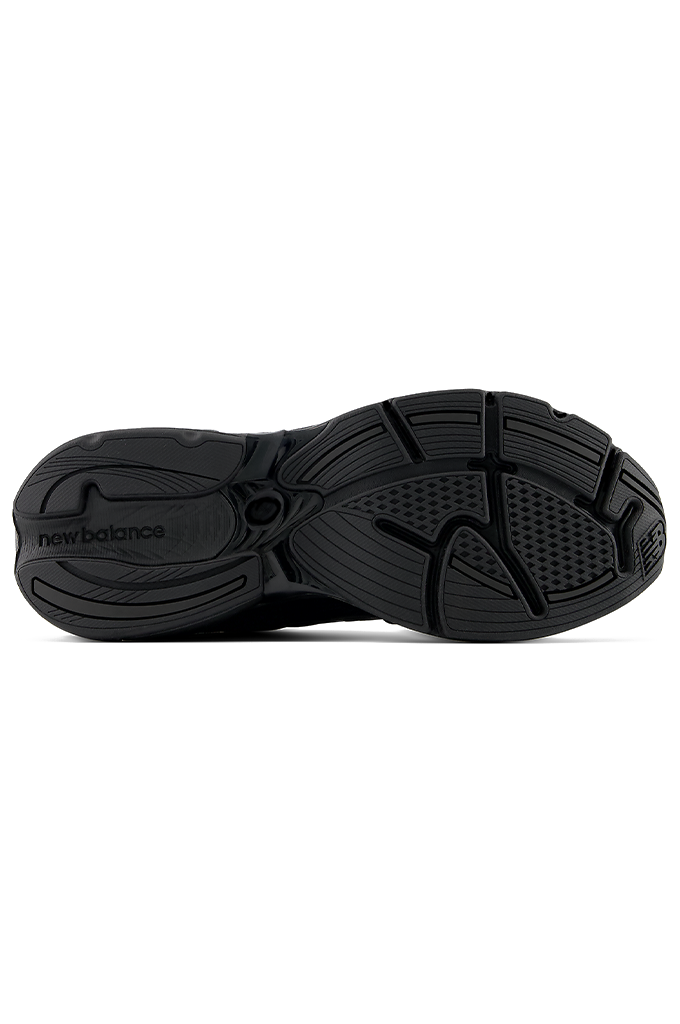 A bottom sole view of a New Balance 2010 sneaker in an all-black colorway. The running-style shoe features a dark mesh base with suede overlays, matching black laces, and the signature New Balance "N" logo on the side panel. The entire sneaker, including the thick, segmented midsole and rubber outsole, is uniformly black.#color_black-black