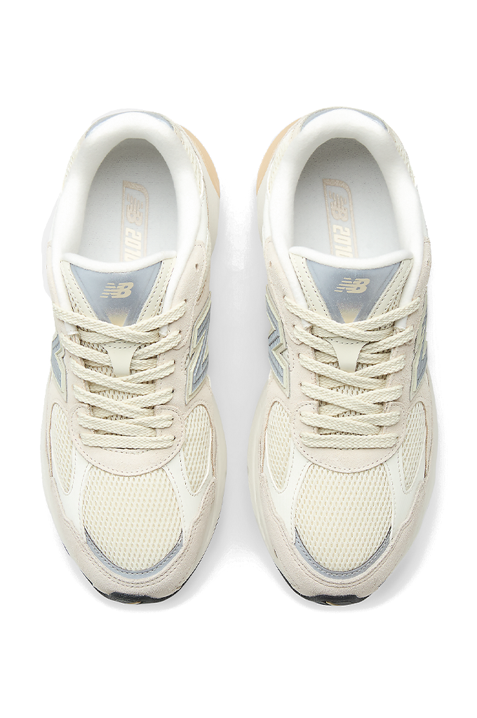 A top view of New Balance sneakers featuring a modern chunky design in shades of grey, cream, and off-white. The shoe has a textured mesh upper with overlapping suede panels, a prominent grey "N" logo on the side, and a thick, multi-layered midsole with a hint of peach coloration near the heel.#color_timberwolf-turtledove