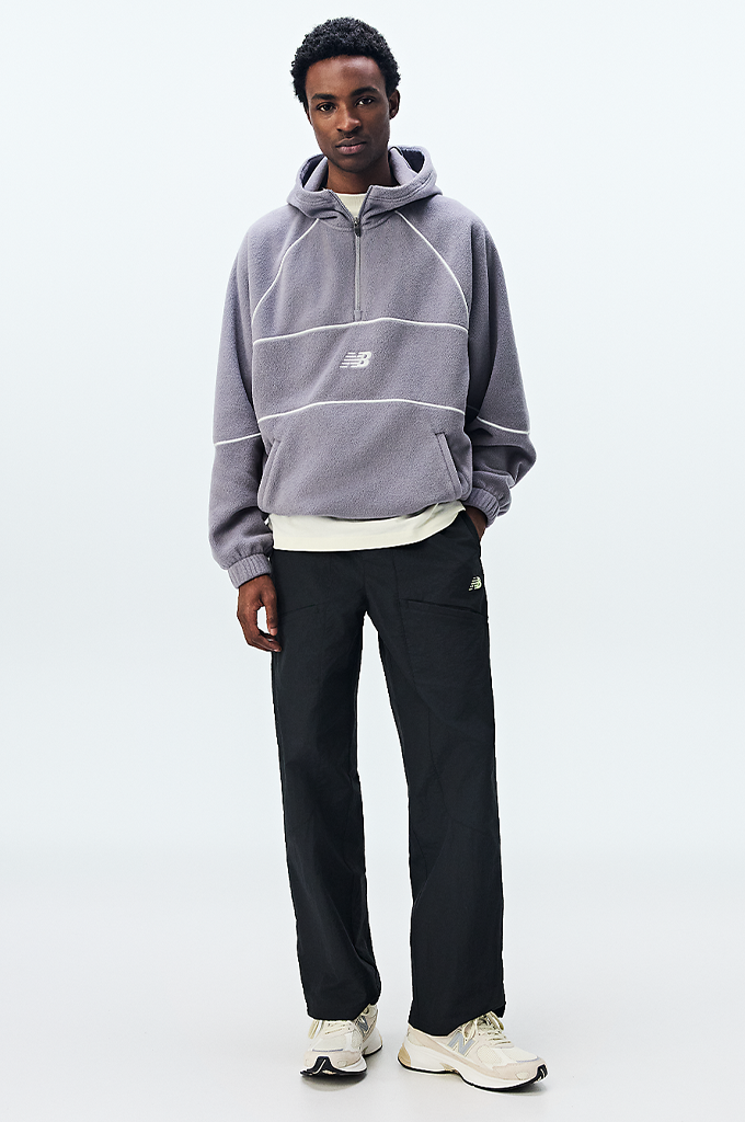 A guy wearing New Balance sneakers featuring a modern chunky design in shades of grey, cream, and off-white. The shoe has a textured mesh upper with overlapping suede panels, a prominent grey "N" logo on the side, and a thick, multi-layered midsole with a hint of peach coloration near the heel.#color_timberwolf-turtledove