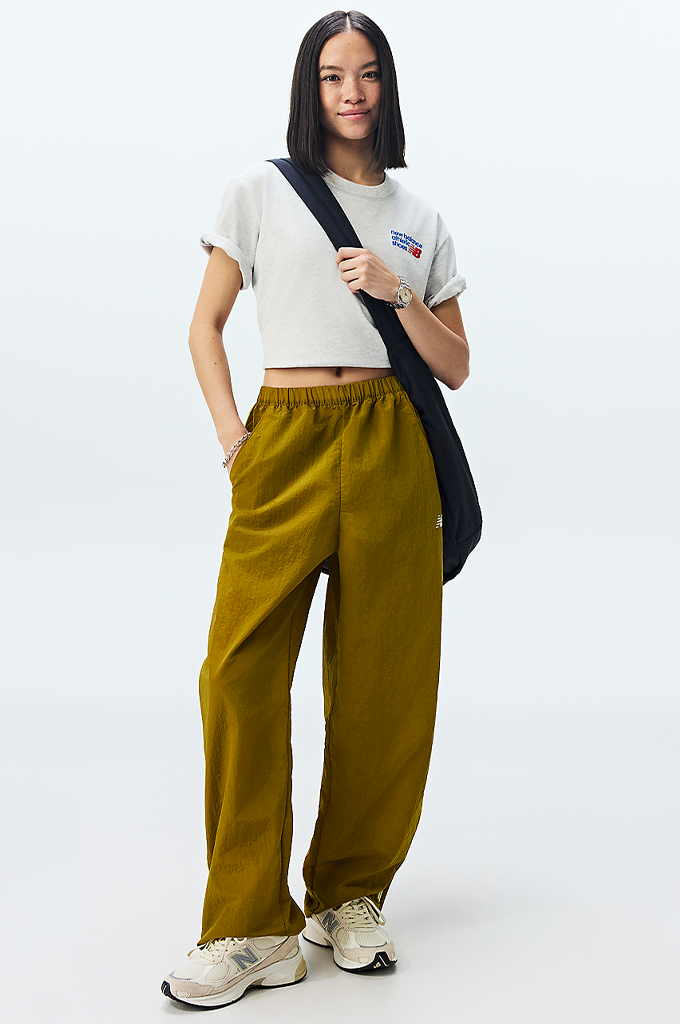A girl wearing New Balance sneakers featuring a modern chunky design in shades of grey, cream, and off-white. The shoe has a textured mesh upper with overlapping suede panels, a prominent grey "N" logo on the side, and a thick, multi-layered midsole with a hint of peach coloration near the heel.#color_timberwolf-turtledove