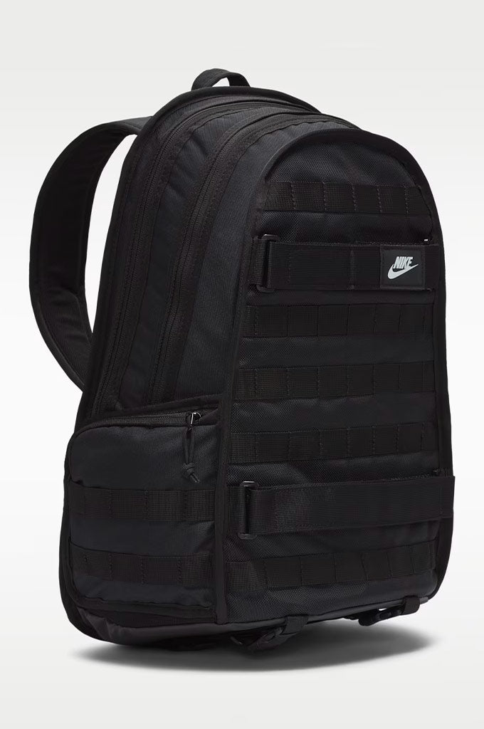 A black Nike backpack with multiple zippered compartments and a white Nike logo patch on the front, shown against a light gray background.#color_black