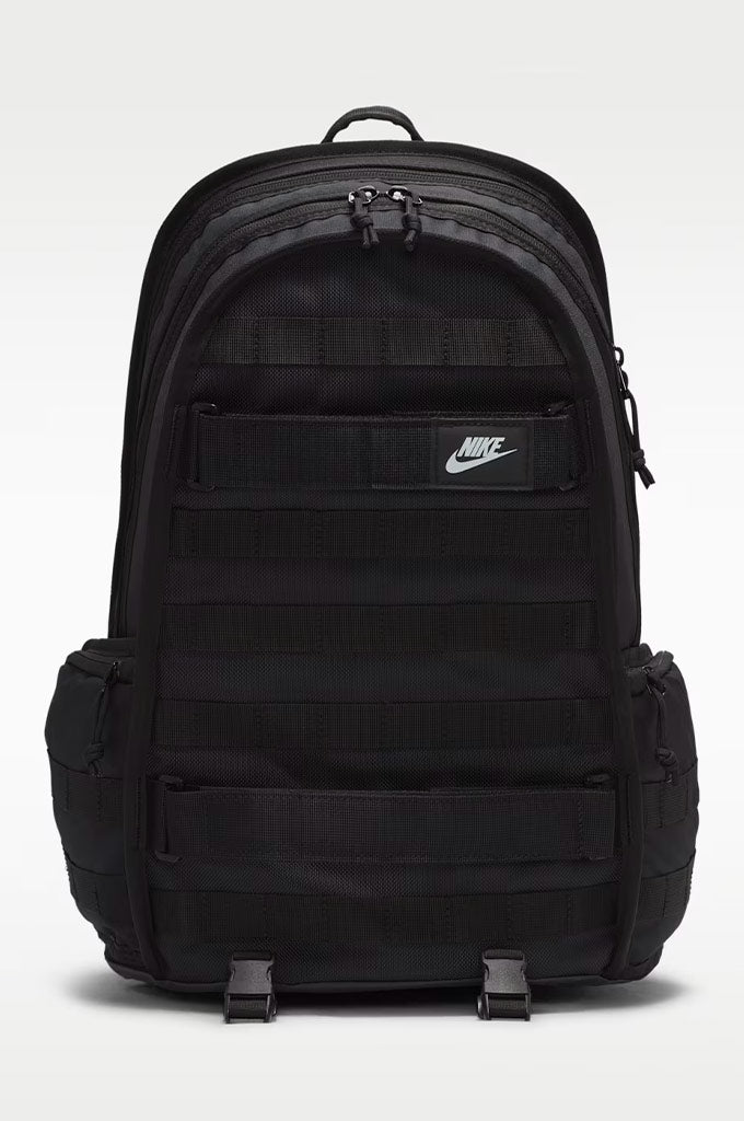 A black Nike backpack with multiple zippered compartments, webbing straps, and side pockets, shown against a light gray studio background.#color_black