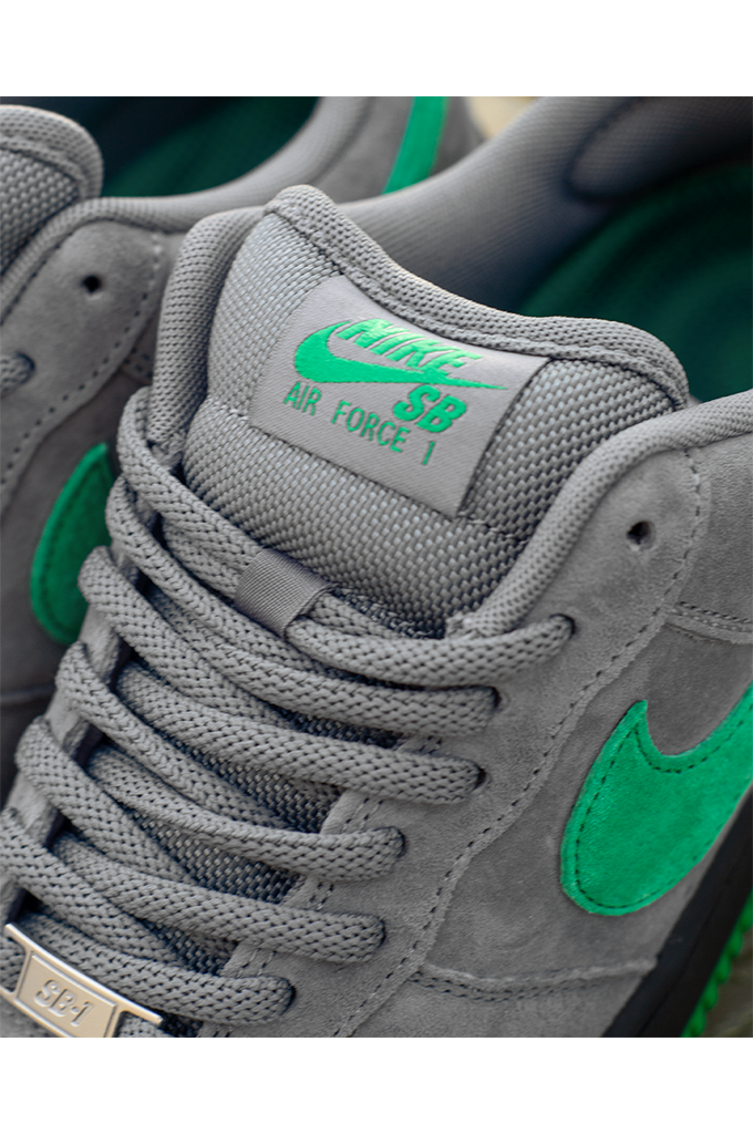 Close up of tongue on Nike SB Air Force 1 Low SE Nocturnal City Pack sneakers in cool grey suede with a court green swoosh and black midsole.