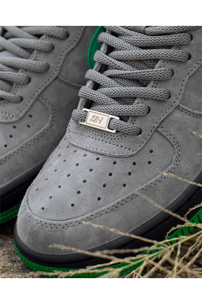 Close up of Nike SB Air Force 1 Low SE Nocturnal City Pack sneakers in cool grey suede with a court green swoosh and black midsole.