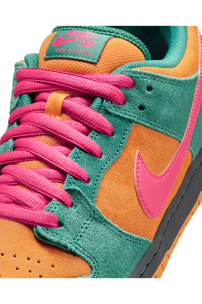 Close-up of a Nike SB Dunk sneaker featuring teal green suede overlays, bright orange suede panels, hot pink laces, and a hot pink Swoosh on a white background.