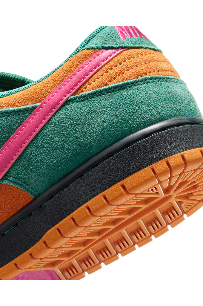 Close-up of a low-top sneaker showing the heel and side panel, with green suede overlays, orange suede sections, a bright pink stripe, a black midsole, and an orange gum outsole on a white background.