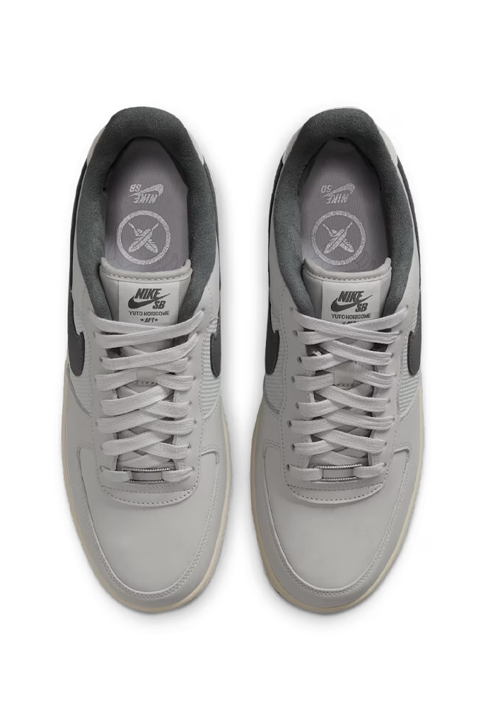 A pair of Nike Air Force 1 Low sneakers in light gray and dark gray, shown from a top-down view on a white background.