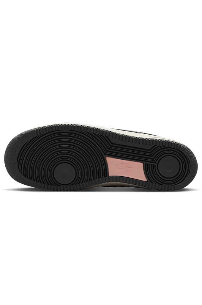The outsole of a sneaker, showing a black treaded rubber bottom with a pink heel accent and a white top edge, photographed against a solid white background.