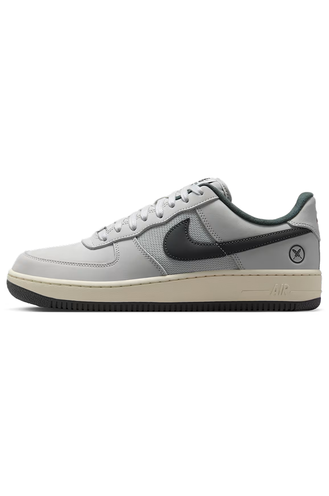 A Nike SB Air Force 1 Low sneaker in light gray with a black Swoosh, black outsole, and a cream-colored midsole.