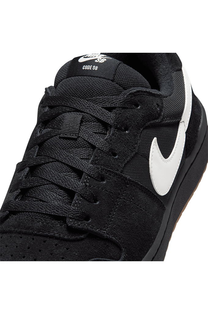 Close-up of a black Nike sneaker with a white Swoosh logo on the side, black laces, and a black tongue label reading 'CODE 58'.