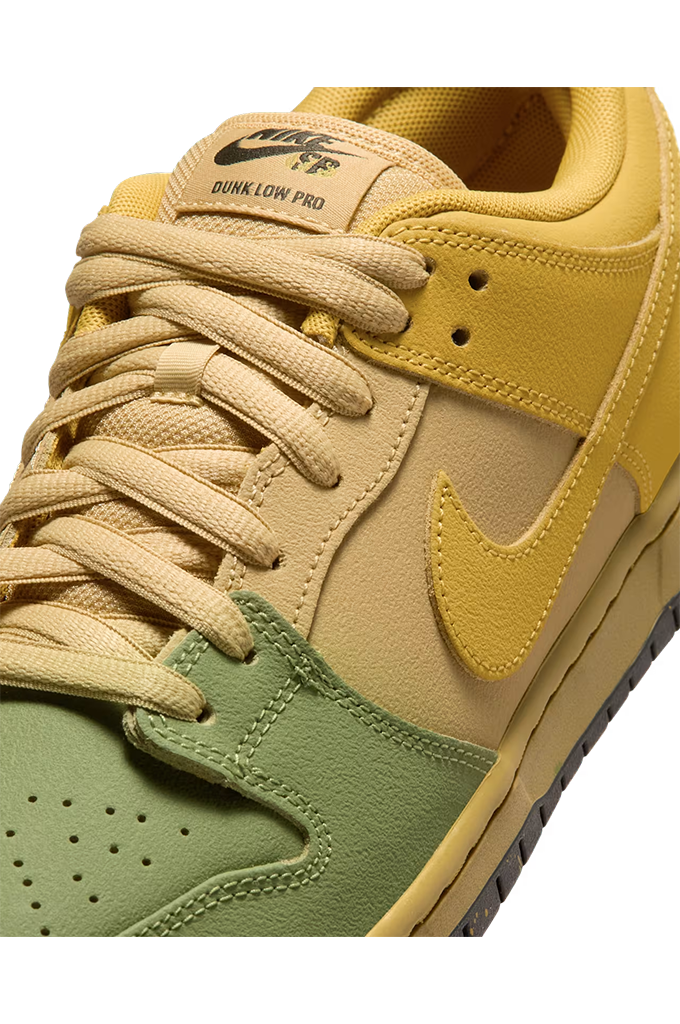 Close-up of a Nike Dunk Low Pro sneaker in yellow, beige, and olive green, showing the side panel, laces, and tongue with 'DUNK LOW PRO' text.