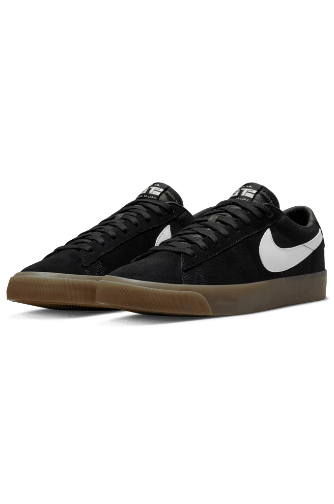 A pair of Nike low-top skate shoes in black suede with a white Swoosh and a brown gum sole, shown against a plain white background.#color_black-white-black-white