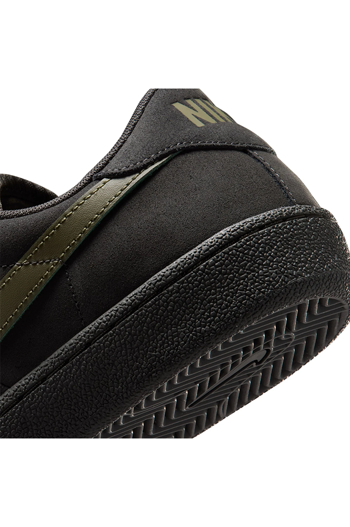 Close-up of a black Nike sneaker showing the heel, textured rubber sole, and olive green stitching and logo details on a white background.