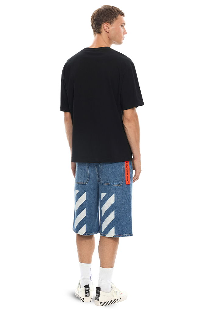 Back of a man wearing blue denim shorts and black shirt on a white background. 