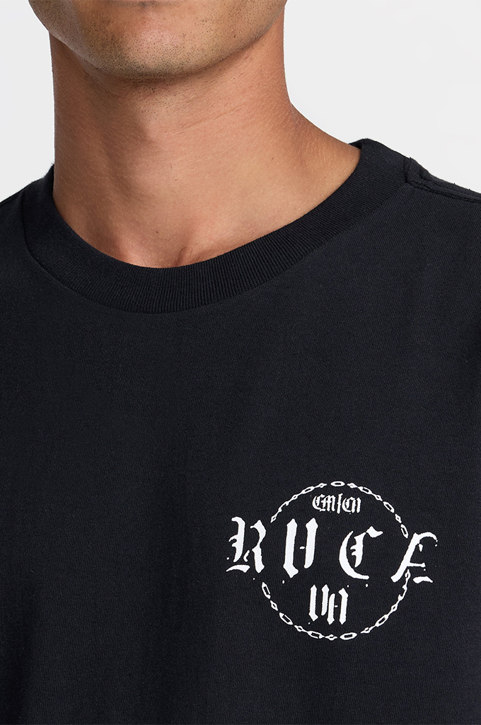 Close-up of a person wearing a black crewneck t-shirt with a white graphic print on the left chest reading 'RVCA' inside a circular chain design.