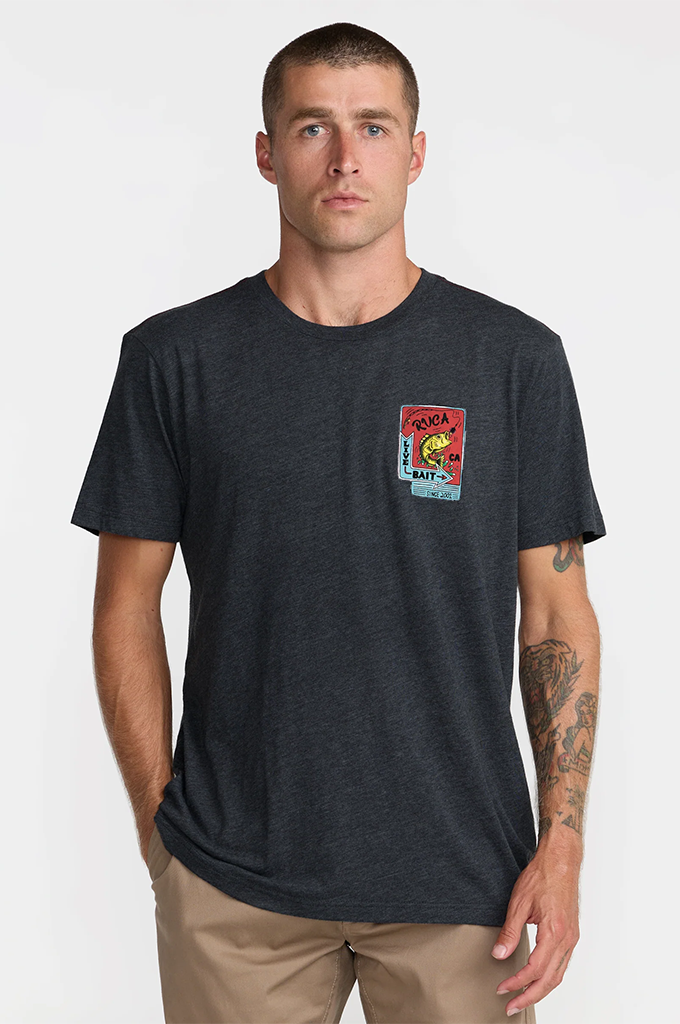 A man wearing a dark charcoal gray heather t-shirt with a colorful graphic on the left chest, paired with khaki pants, against a light gray background.#color_black