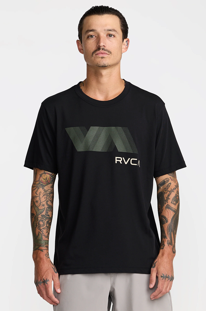 A man wearing a black short-sleeve t-shirt with a large dark green and white RVCI logo on the chest, paired with light gray pants, against a plain light gray background.#color_black