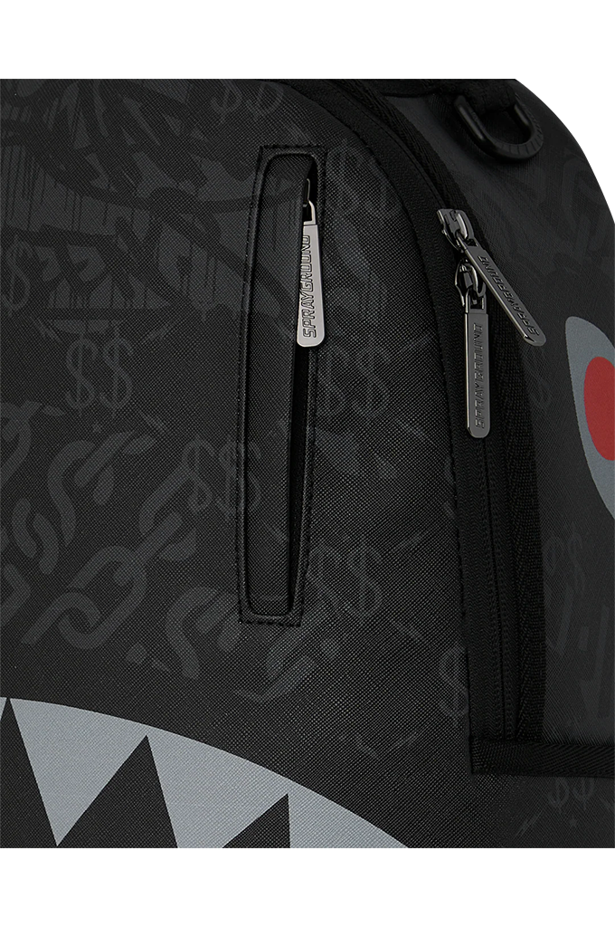 Close-up of a black backpack featuring a subtle shark and dollar-sign pattern, with a vertical zippered pocket and silver zipper pulls.