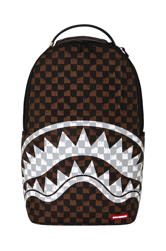 A Sprayground Shark backpack featuring a brown and black checkered pattern, a large white shark mouth graphic across the front, and a small red Sprayground logo tag at the bottom right.