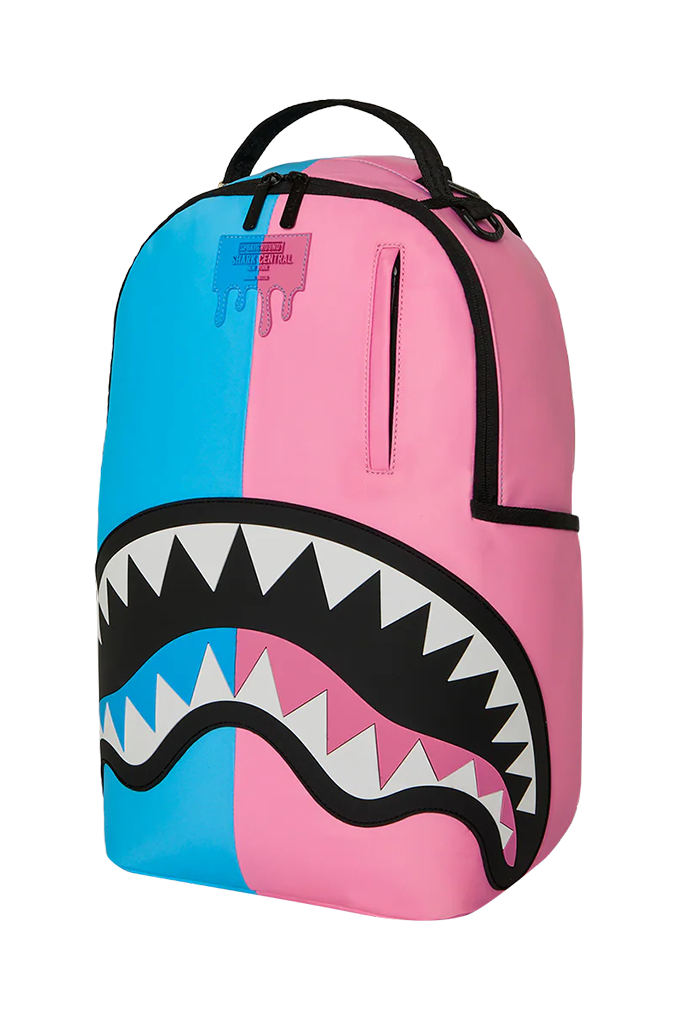 A Sprayground Shark backpack in a split blue and pink colorway, featuring a large shark mouth graphic with black, white, and pink details on the front.