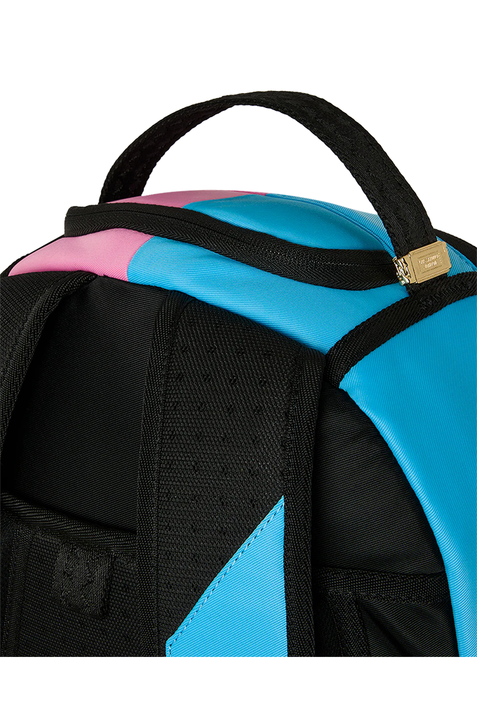 Close-up of a backpack showing black webbing straps, a bright cyan blue panel, a pink panel, and a small gold zipper pull on a white background.