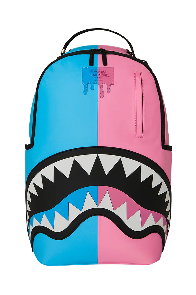 A Sprayground Shark backpack in a split blue and pink colorway, featuring a large shark mouth graphic with black, white, and pink details on the front.