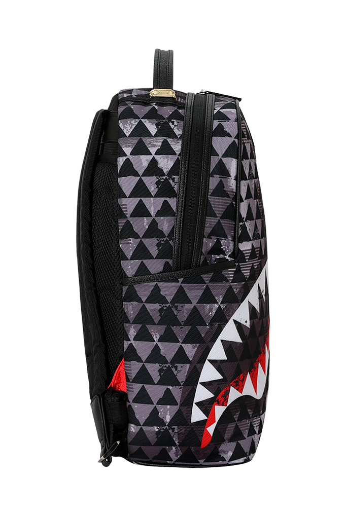 A backpack featuring a black and gray distressed geometric triangle pattern with a shark mouth graphic in white and red on the lower right side.