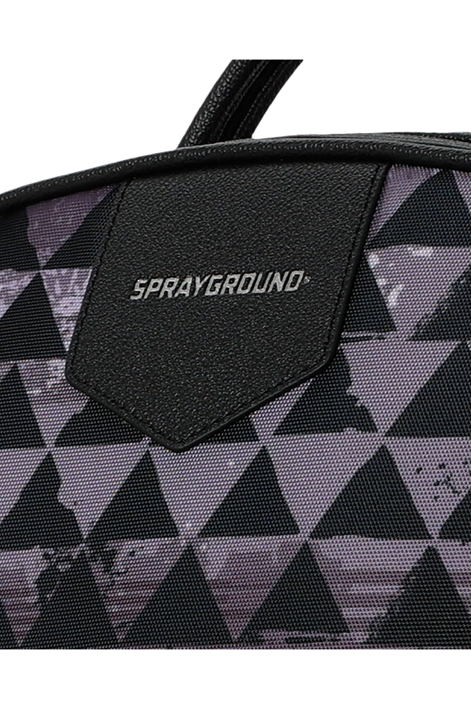 Close-up of a Sprayground bag featuring a black and gray geometric triangle pattern with a black leather brand patch on the front.